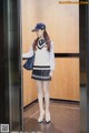 A woman in a school uniform is standing in an elevator.