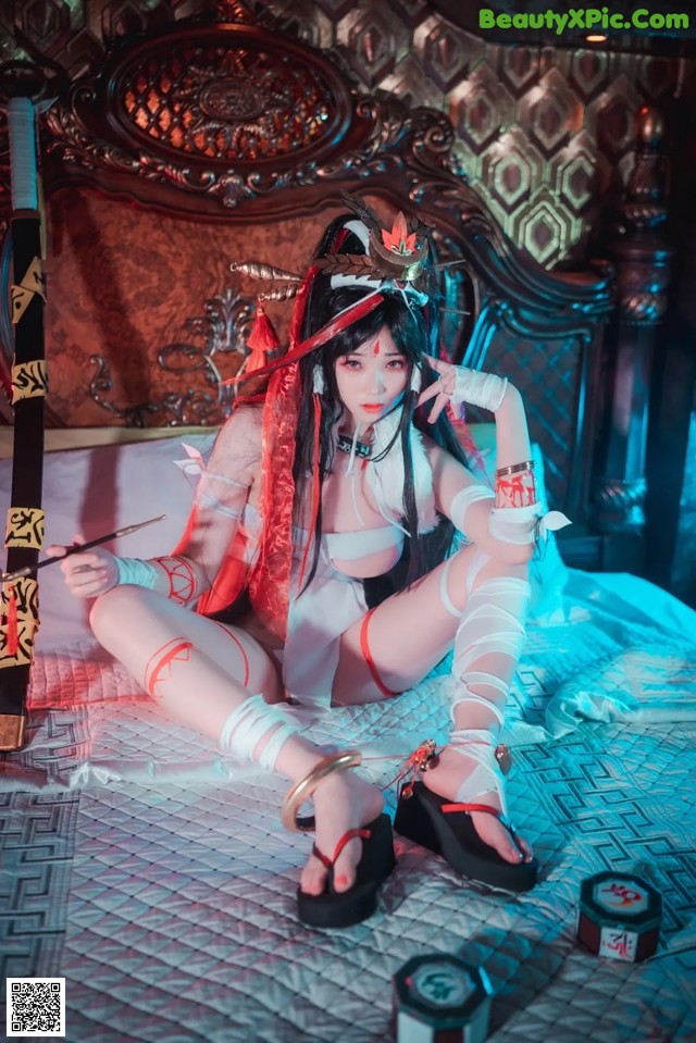 A woman sitting on a bed holding a sword.