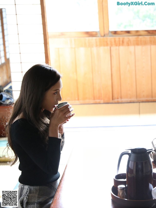 A woman sitting at a table with a cup of coffee.