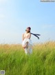 A naked woman standing in a field of tall grass.