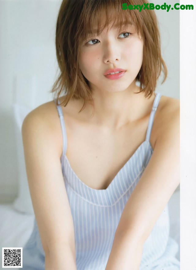 A woman in a blue dress sitting on a bed.